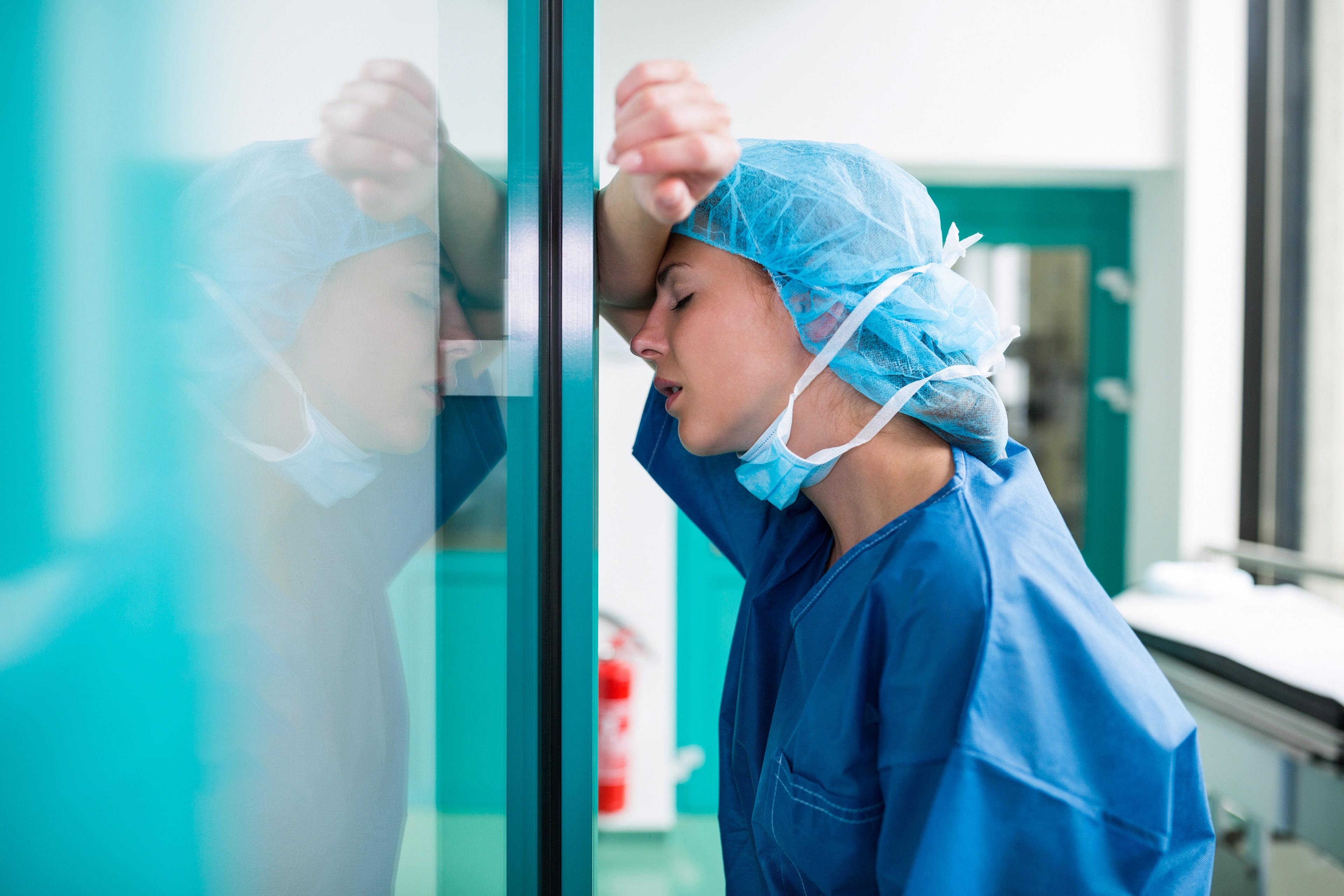 tired doctor leaning against doorway