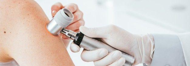 panoramic shot of dermatologist in latex glove holding dermatoscope while examining patient