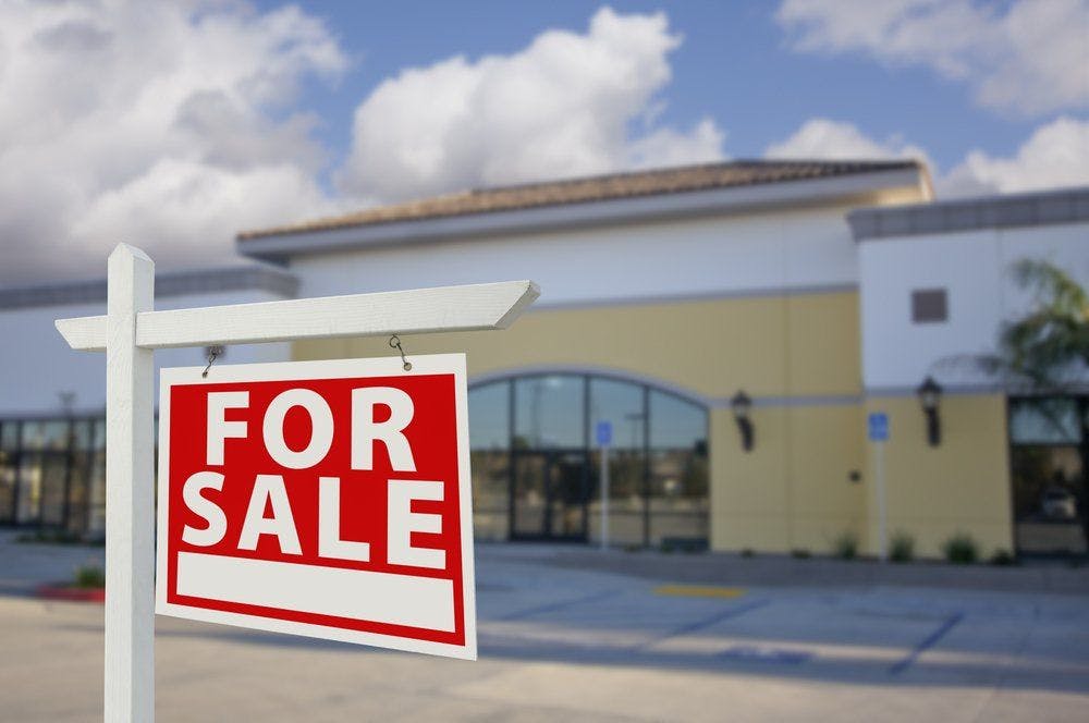 For sale sign in front of building